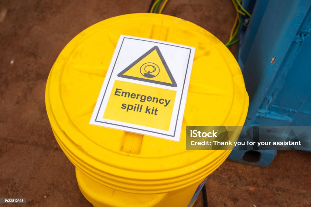 "Emergency spill kit" yellow plastic containment box. Safety sign and symbol at industrial equipment.